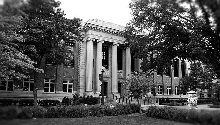 Black and white photo of large building with columns surrounding the entrance.